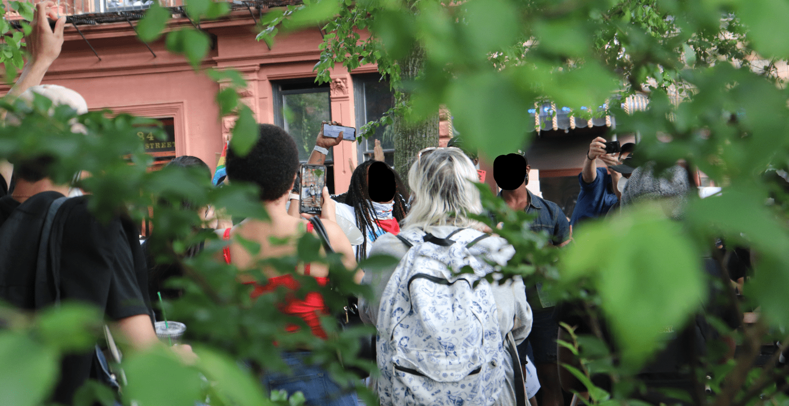 Surrounded by greenery at every angle, a group of activists and protestors raise their fists in Christopher Park, Manhattan. Photo by author.