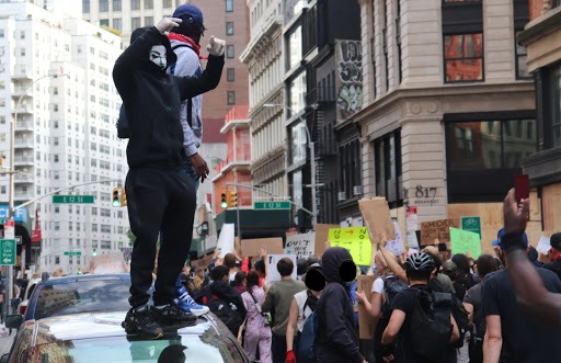 Two people stand on a car mere blocks away from Union Square, as rows of people next to them march in the streets. Photo by author.