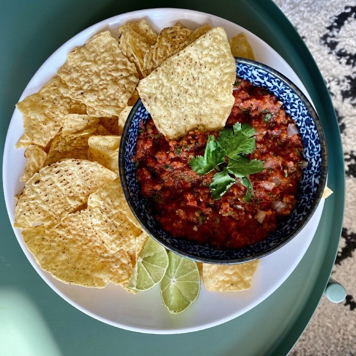 Photo of chips and salsa roja on a green plate.